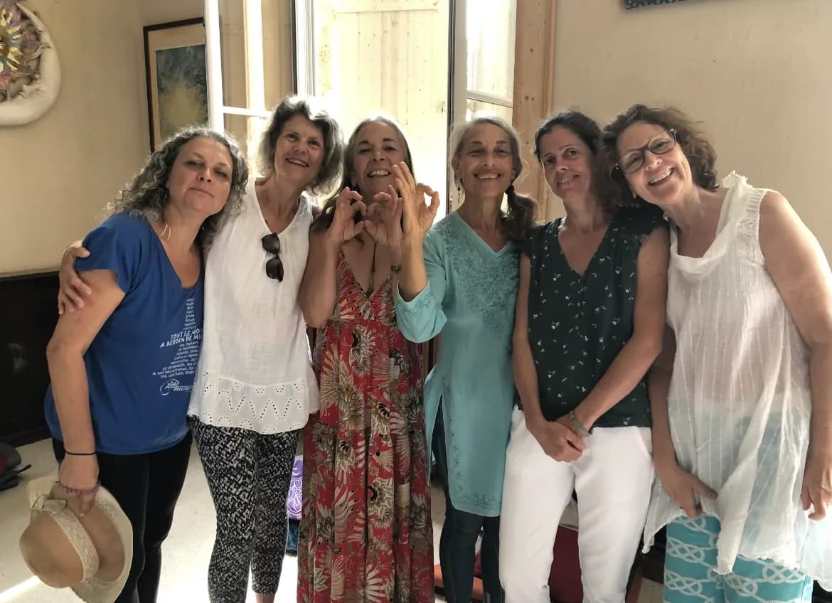 Six femmes souriantes réunies après un cours, l'une d'elles formant un coeur avec ses mains