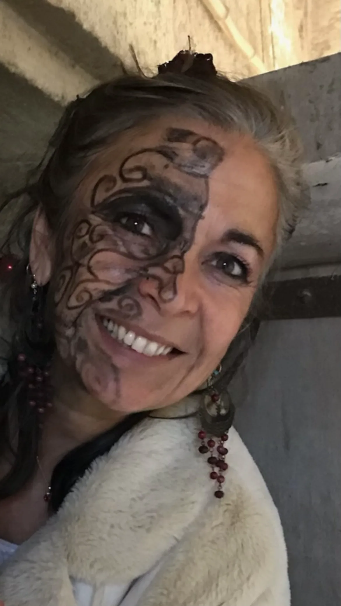 Portrait souriant de Chantal Lassier, un motif peint sur le visage lors d'une cérémonie